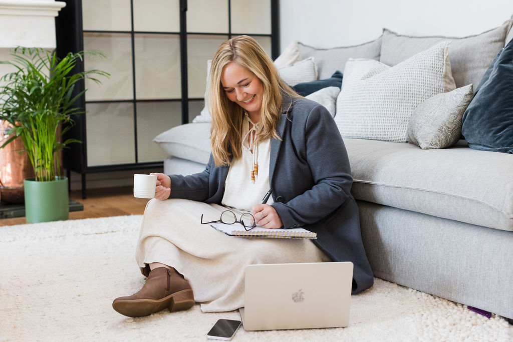 Kobie working from the floor with her notebook and coffee